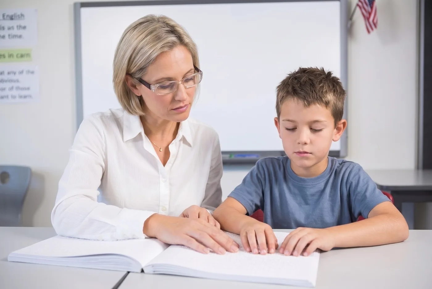 A young boy learning braille with the help of his orientation and mobility guide